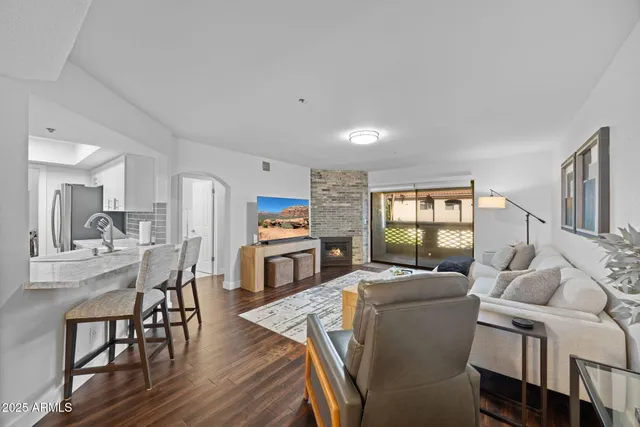 a living room with furniture a fireplace and a kitchen view
