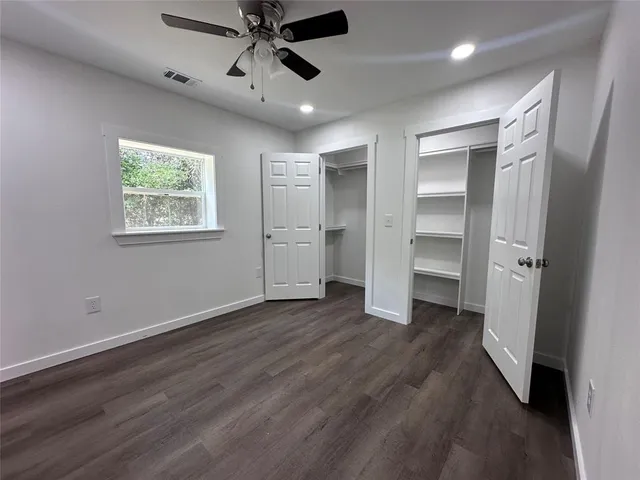 an empty room with wooden floor closet and windows