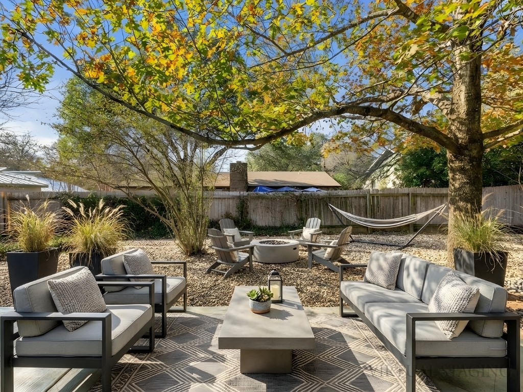 a view of patio with table and chairs potted plants and large tree