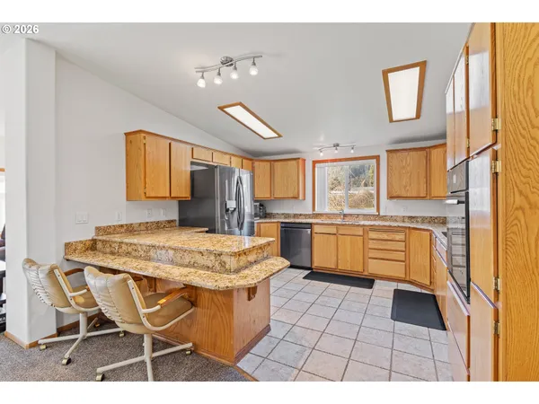 a open kitchen with a stove a sink dishwasher and white cabinets with wooden floor