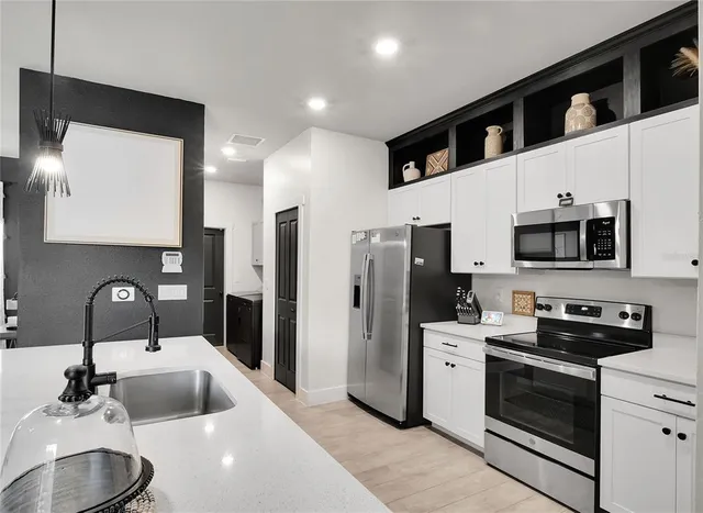 a kitchen with stainless steel appliances a sink a stove a refrigerator a microwave a sink and cabinets