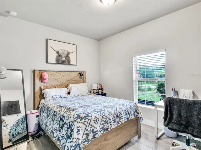 a bedroom with a bed and chair with a large window