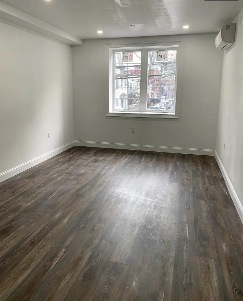 37-28 104th Street Queens, NY 11368 - Photo 5 of 11 an empty room with wooden floor and windows