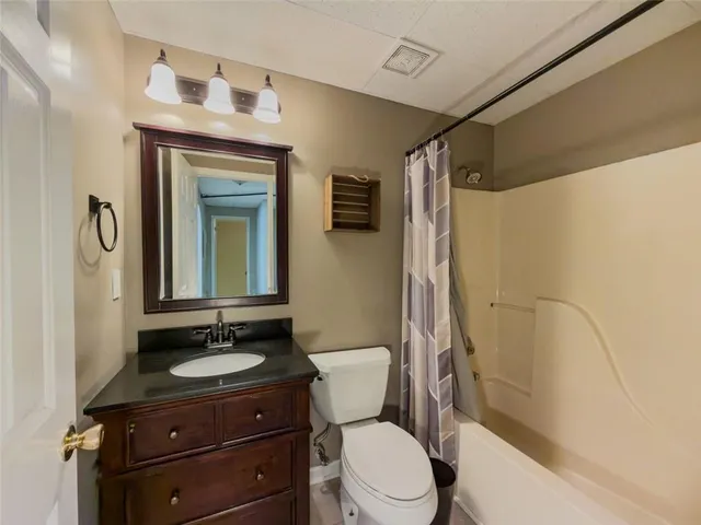 a bathroom with a granite countertop sink toilet mirror and shower