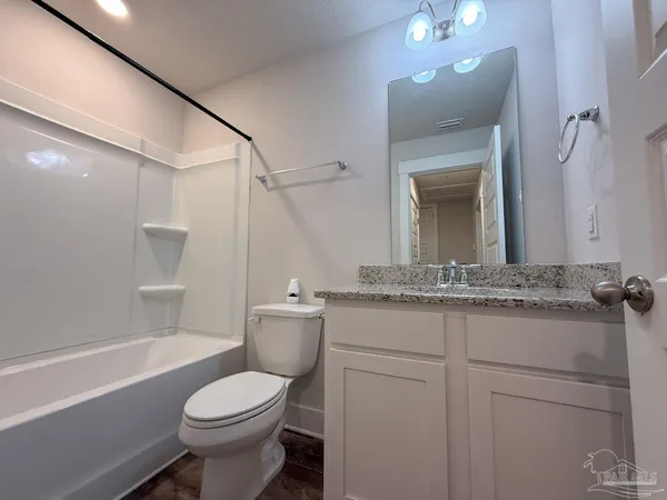 a bathroom with a granite countertop toilet sink and mirror