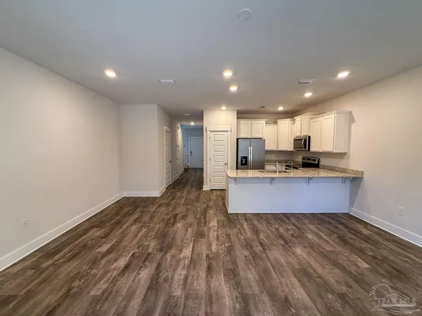 a large kitchen with stainless steel appliances a large counter top a stove and a refrigerator