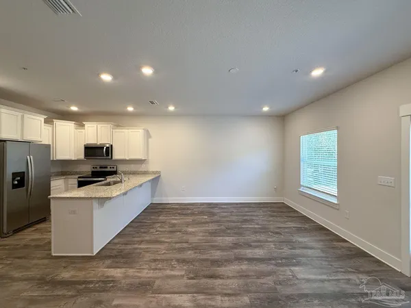 a kitchen with stainless steel appliances kitchen island a stove top oven a sink a refrigerator and white cabinets