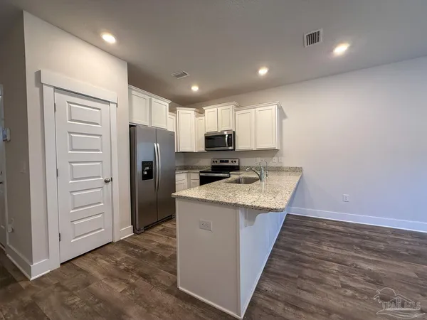 a kitchen with stainless steel appliances granite countertop a refrigerator and a stove top oven