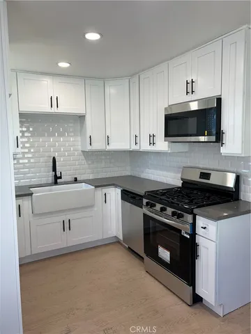a kitchen with stainless steel appliances white cabinets and a stove a sink