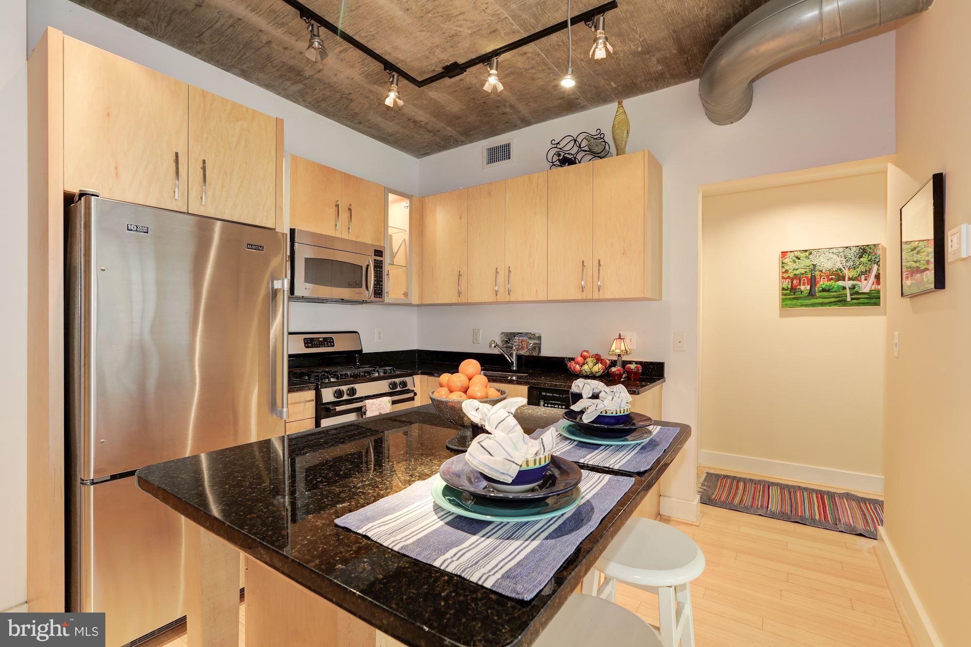 a kitchen with stainless steel appliances granite countertop a sink refrigerator and cabinets