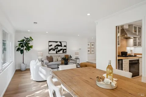 a dining room with wooden floor a chandelier a glass table and chairs
