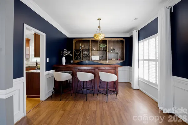 a dining room with wooden floor a chandelier a wooden table and chairs