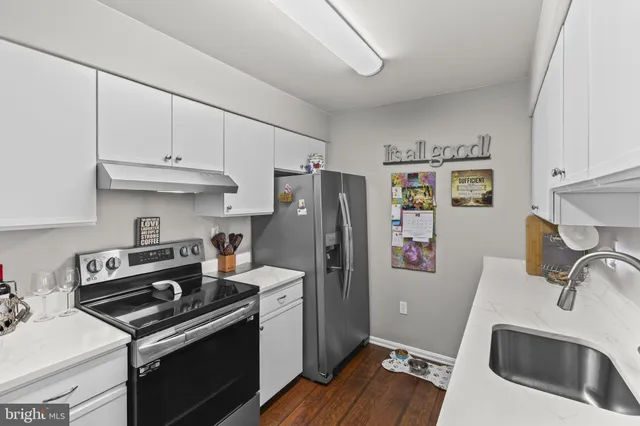 a kitchen with stainless steel appliances a stove a refrigerator and a sink with wooden floor