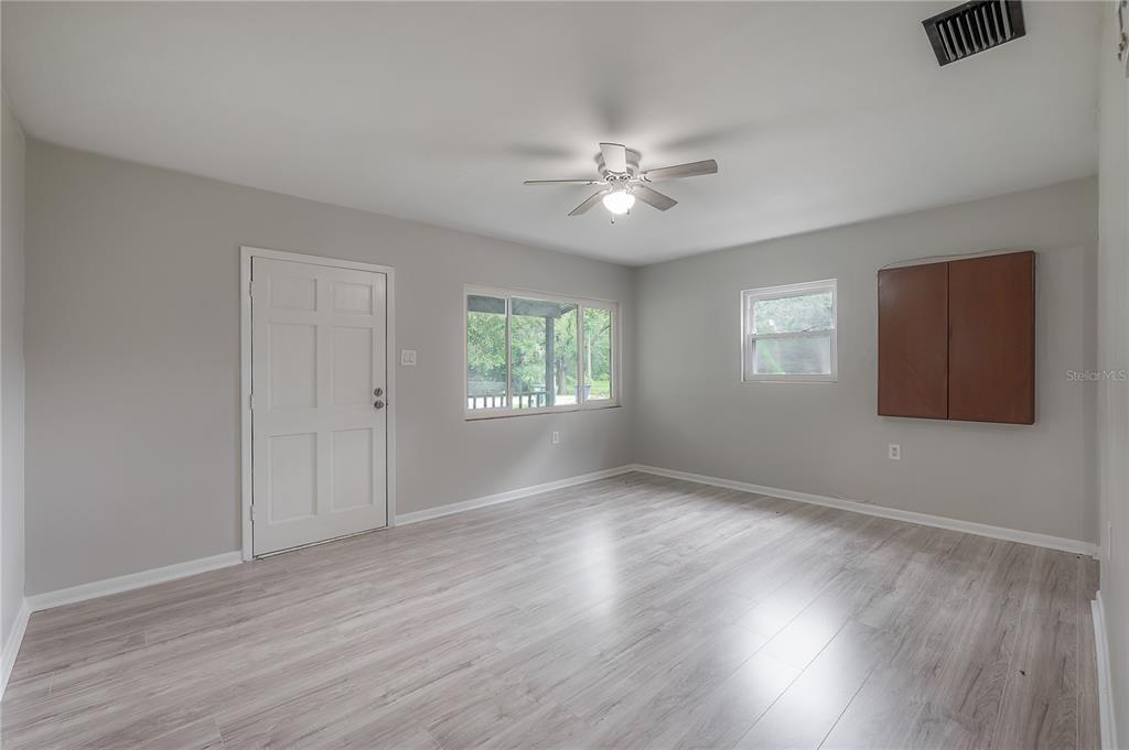 10411 North Woodmere Road Tampa, FL 33617 - Photo 6 of 29 a view of an empty room with wooden floor and a window