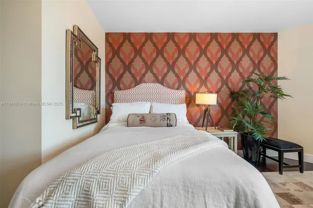 a bedroom with a bed and chair with potted plant