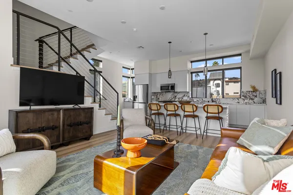 a dinning area with stainless steel appliances granite countertop a dining table chairs and a refrigerator