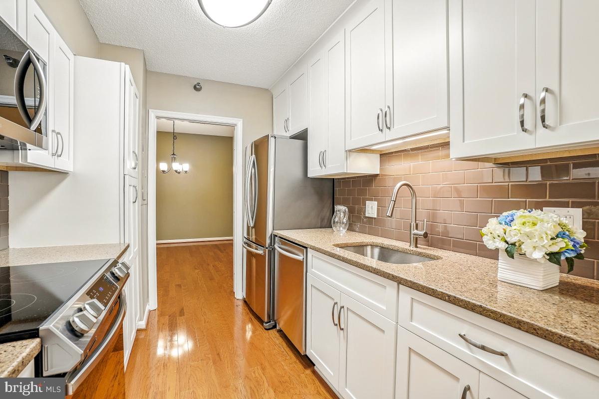 a kitchen with stainless steel appliances granite countertop a sink a stove and cabinets