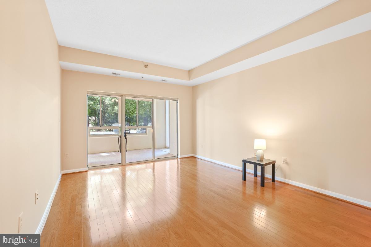 14809 Pennfield Circle, Unit 105 Silver Spring, MD 20906 - Photo 4 of 29 a view of an empty room with wooden floor and a window