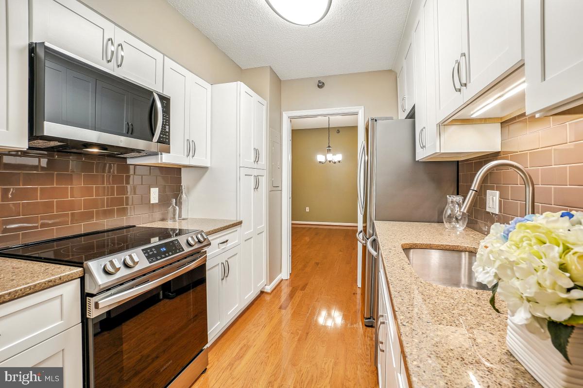 14809 Pennfield Circle, Unit 105 Silver Spring, MD 20906 - Photo 9 of 29 a kitchen with granite countertop a stove and a sink