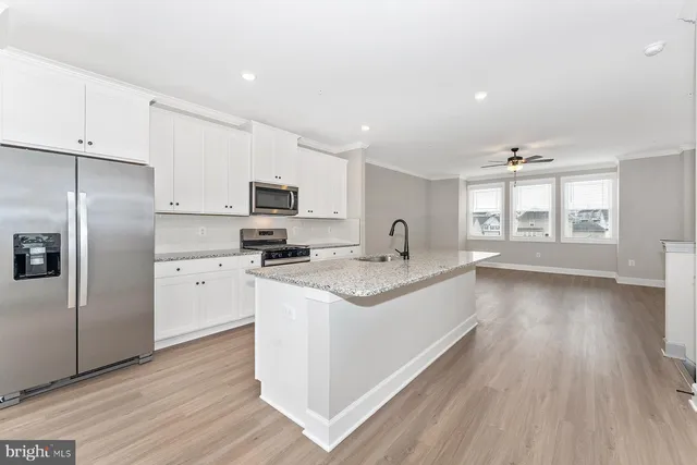 a large kitchen with stainless steel appliances granite countertop a large stove a sink dishwasher and a refrigerator with wooden floor