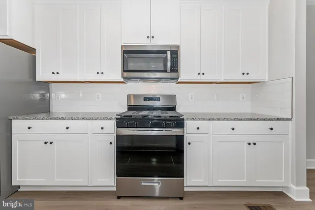 a kitchen with granite countertop white cabinets and stainless steel appliances