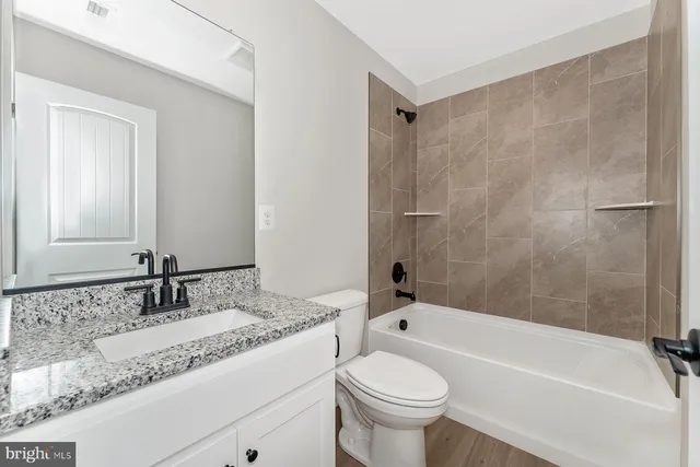 a bathroom with a granite countertop bathtub sink vanity mirror and toilet