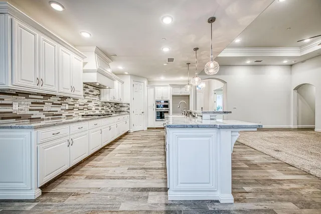 a spacious bathroom with a granite countertop double vanity sink a mirror and a bathtub