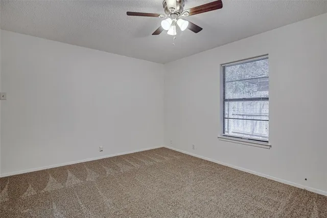 an empty room with a window and a fan