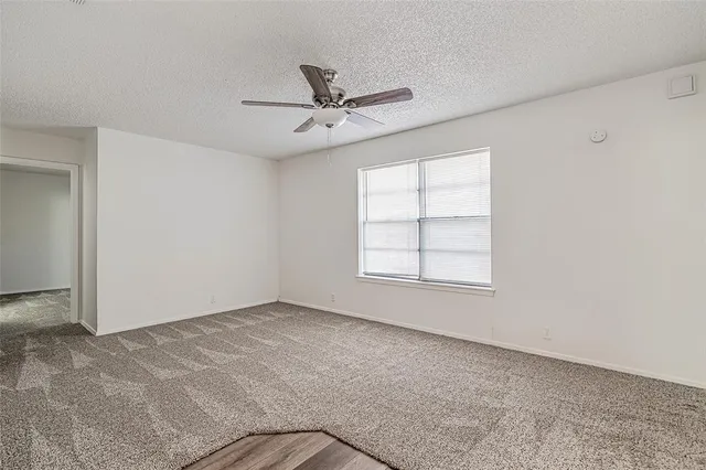an empty room with a window and a fan