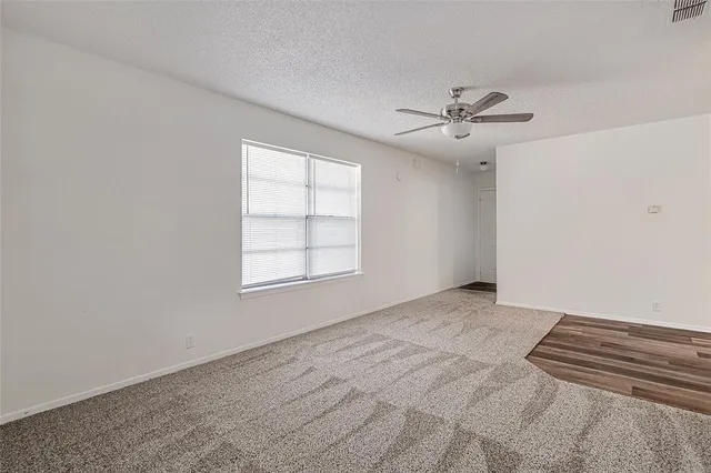 an empty room with windows and fan