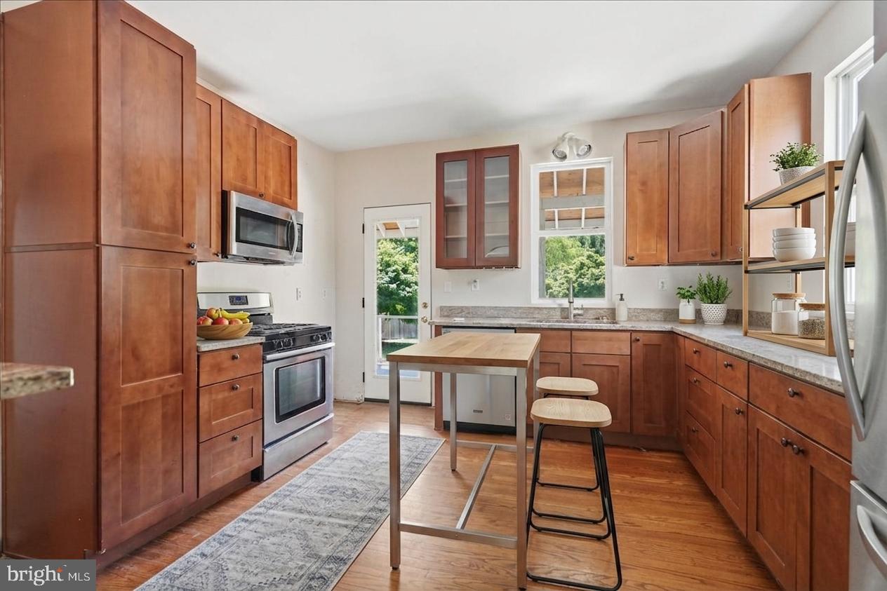 73 Church Road Arnold, MD 21012 - Photo 7 of 29 a kitchen with stainless steel appliances granite countertop a stove a sink dishwasher a microwave oven and a refrigerator with wooden cabinets