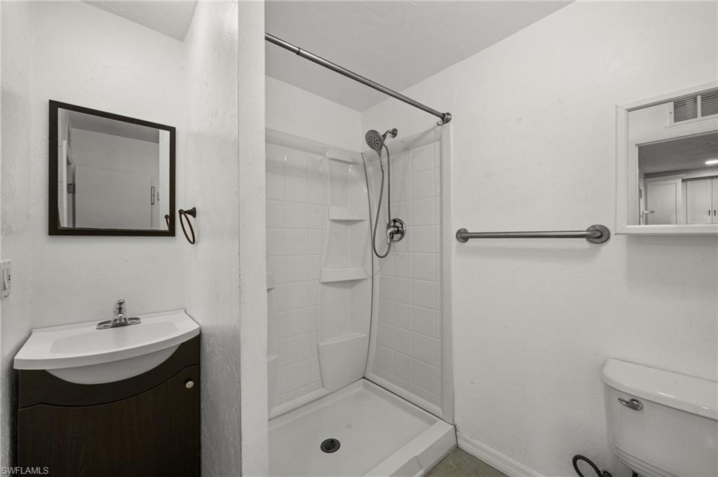 715 10th Street North Naples, FL 34102 - Photo 14 of 36 a bathroom with a shower sink mirror and toilet