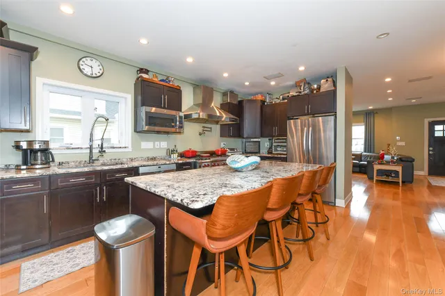a kitchen with stainless steel appliances granite countertop a table chairs sink and stove top oven