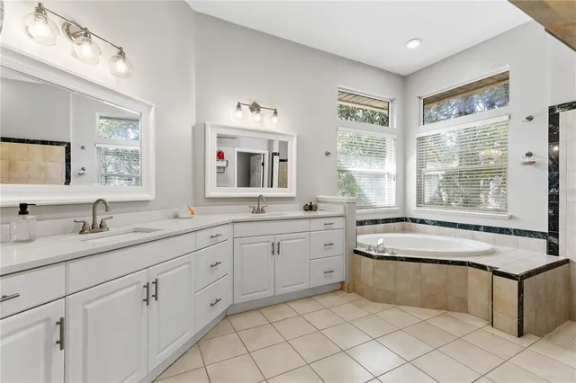 a spacious en suite bathroom with a granite countertop sink and mirror