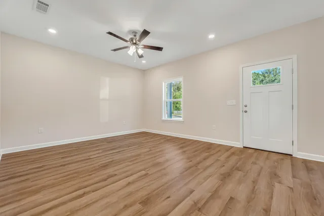 an empty room with wooden floor window and ceiling fan