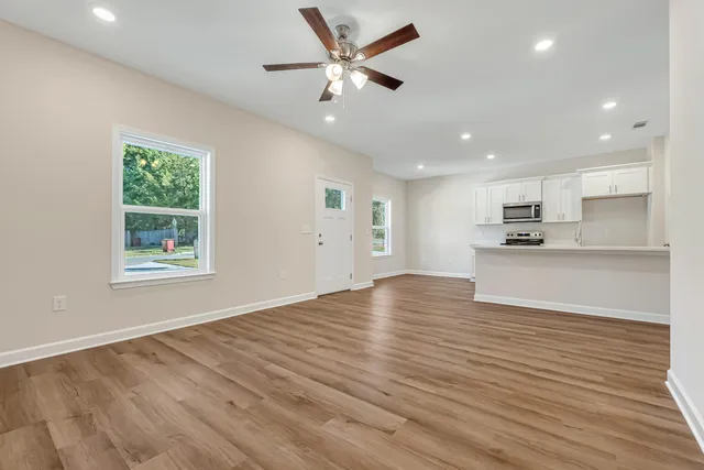 a view of an empty room with window and wooden floor