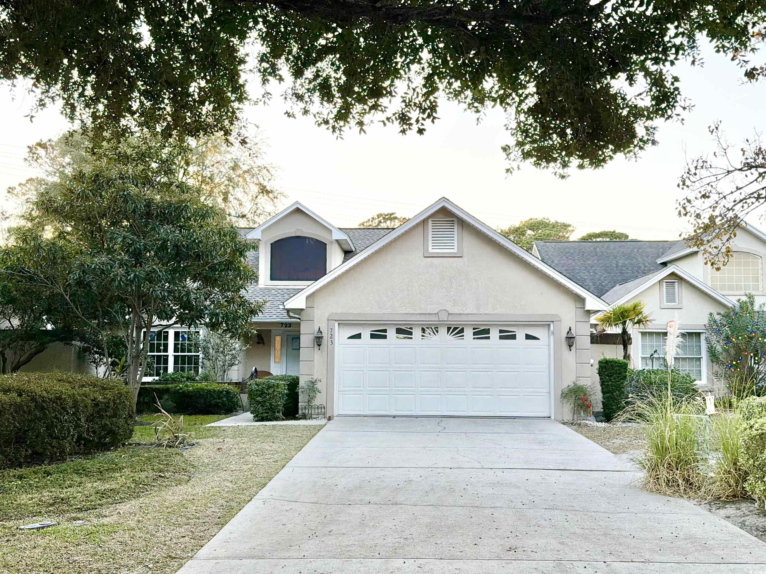 View of front of property featuring stucco siding, an attached garage, driveway, and roof with shingles