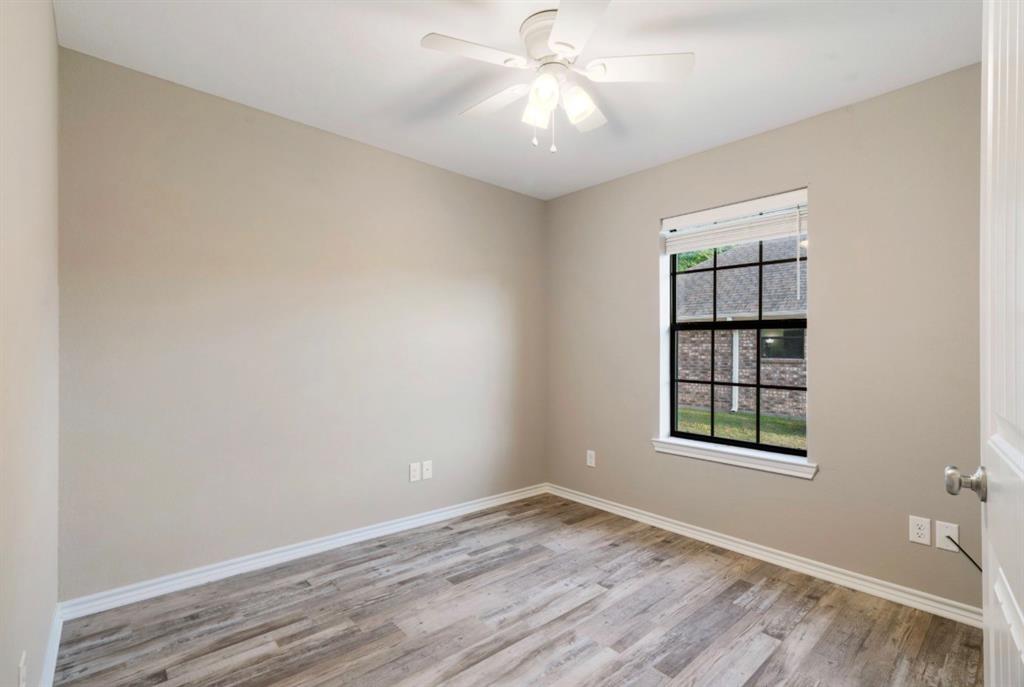 90 44th Street Southwest Paris, TX 75460 - Photo 12 of 17 an empty room with wooden floor chandelier fan and windows