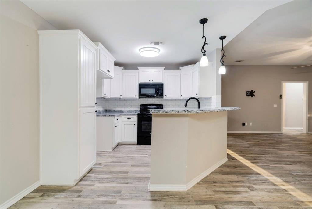 90 44th Street Southwest Paris, TX 75460 - Photo 5 of 17 a kitchen with kitchen island a sink stainless steel appliances and white cabinets