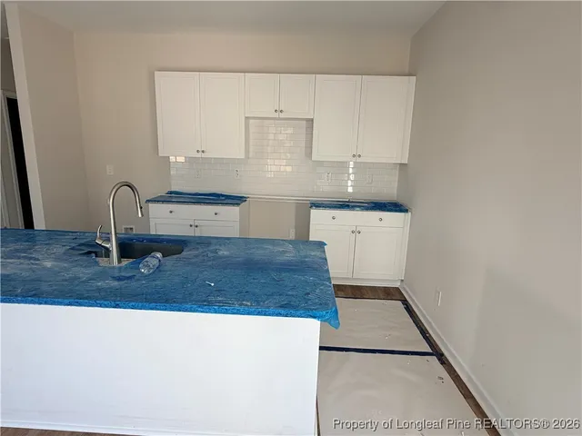 a kitchen with kitchen island a sink a stove and white cabinets