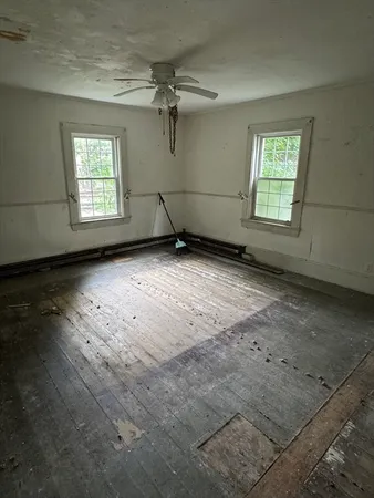 an empty room with wooden floor a ceiling fan and windows