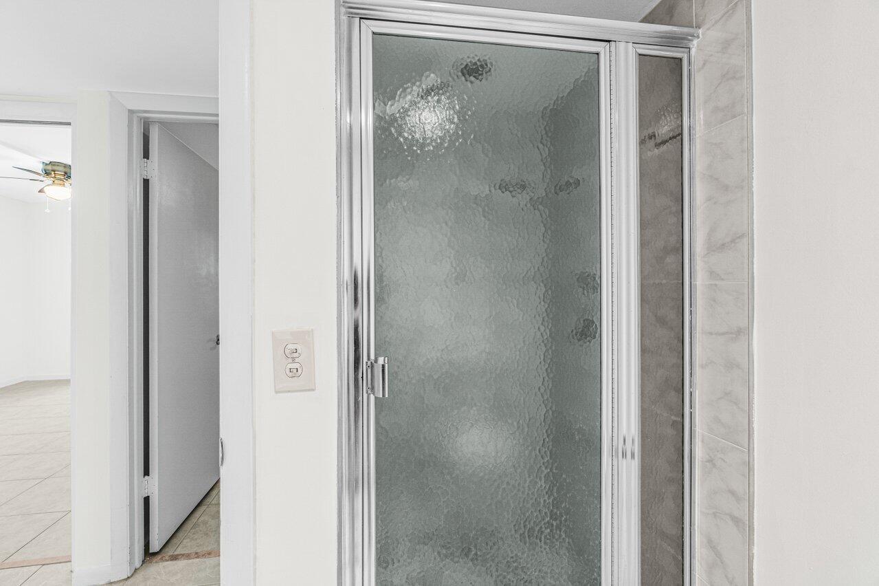 641 Normandy Lane, Unit N Delray Beach, FL 33484 - Photo 13 of 26 a bathroom with a glass shower door and a mirror