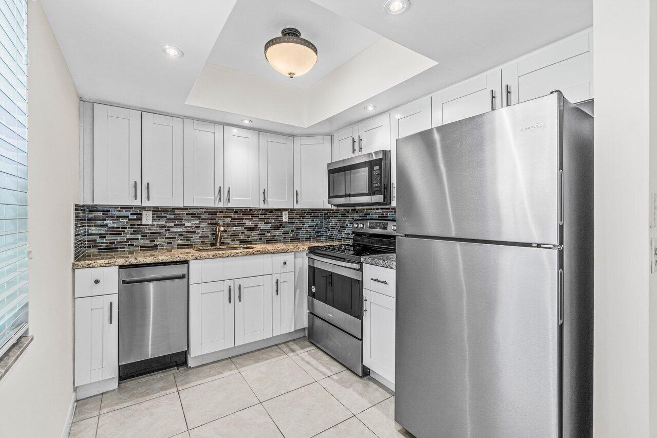 641 Normandy Lane, Unit N Delray Beach, FL 33484 - Photo 3 of 26 a kitchen with stainless steel appliances granite countertop a refrigerator sink and cabinets