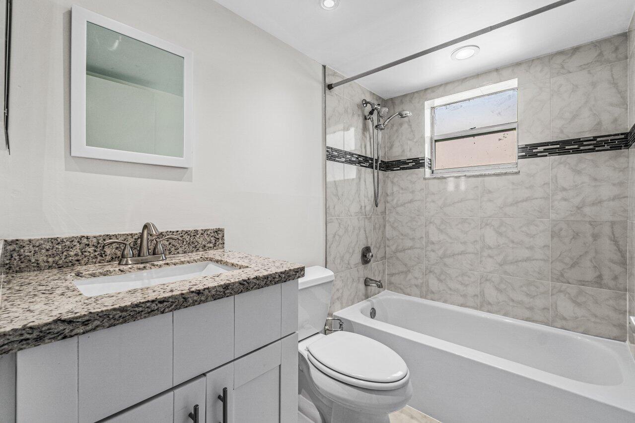 641 Normandy Lane, Unit N Delray Beach, FL 33484 - Photo 9 of 26 a bathroom with a granite countertop sink toilet and shower