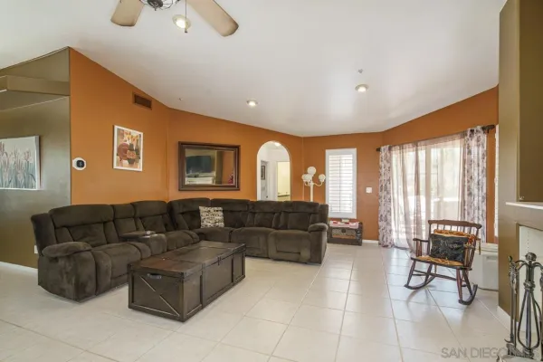 a living room with stainless steel appliances furniture a flat screen tv and a view of kitchen