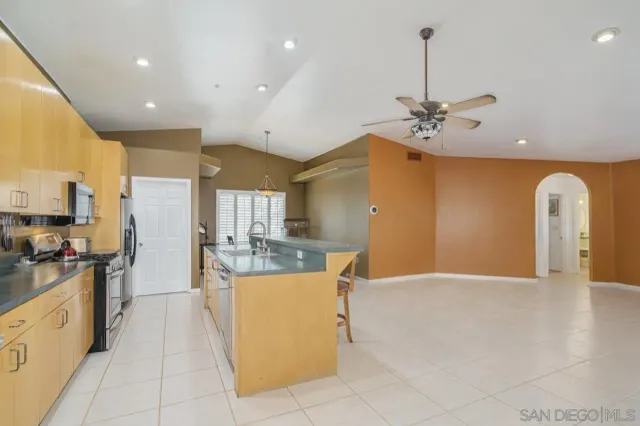 a view of an empty room with a fireplace and a ceiling fan