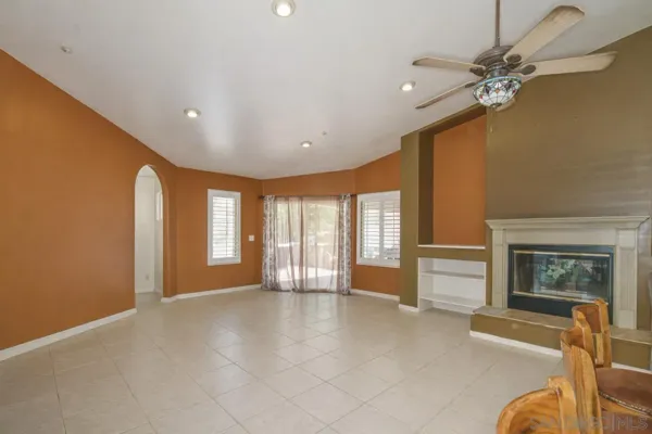 a living room with lots of furniture kitchen view and large windows