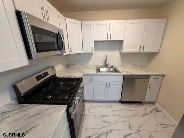 a kitchen with stainless steel appliances a sink a stove a microwave a sink a refrigerator and cabinets