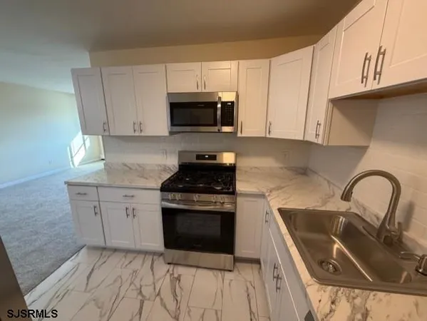 a kitchen with white cabinets a sink and a stove