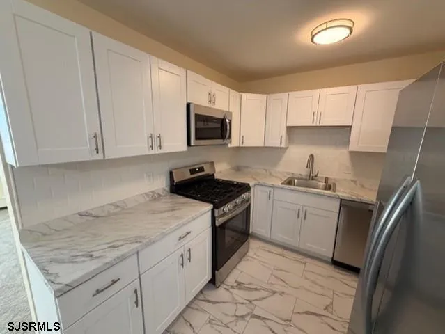 a kitchen with granite countertop white cabinets and stainless steel appliances